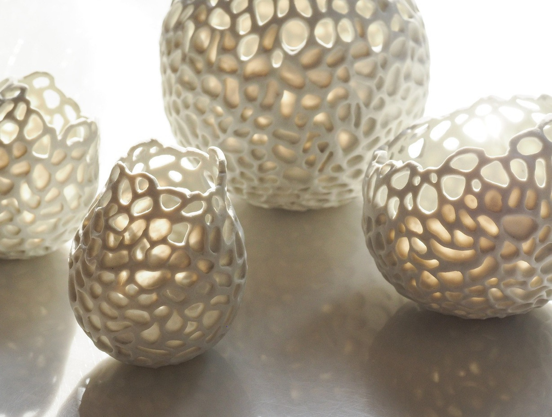 Aurora porcelain vessels, small cluster of pale glazed pieces with carved lattice surfaces, light passing through