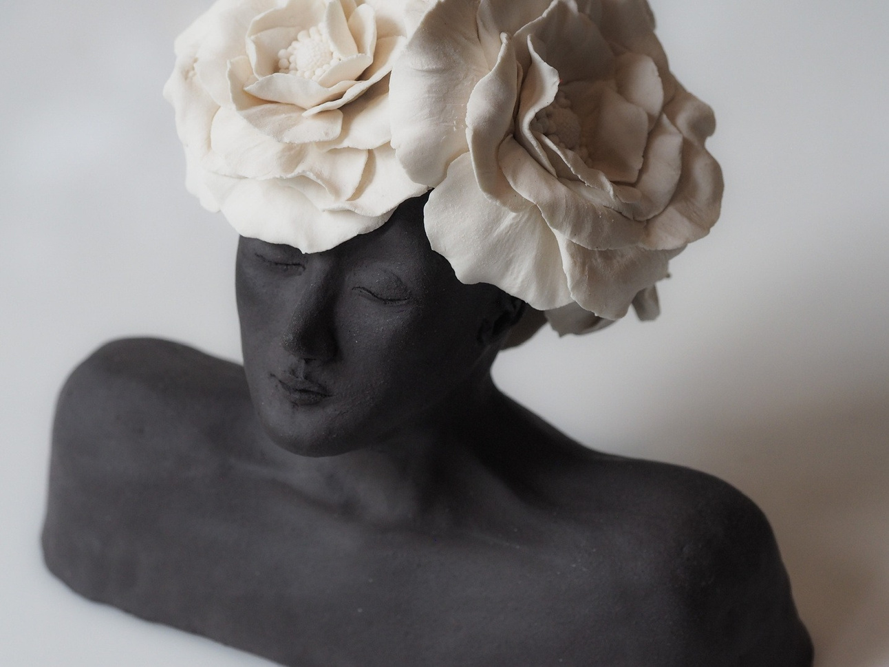 Azra bust, dark stoneware figure with a crown of large white porcelain roses, eyes closed — view 2