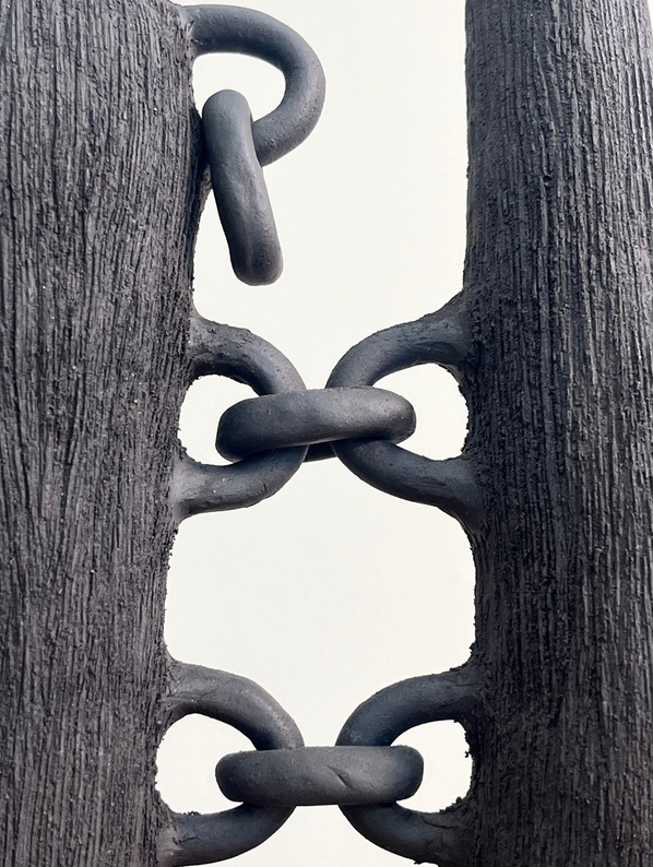 Broken bonds sculpture, two dark stoneware vertical forms connected by hand-rolled clay chains