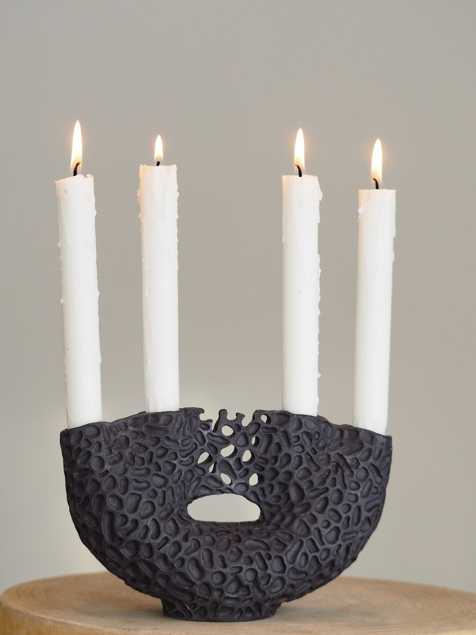 Calliope candle holder, dark stoneware base with carved lace-like surface and four candle holders rising from a shared form