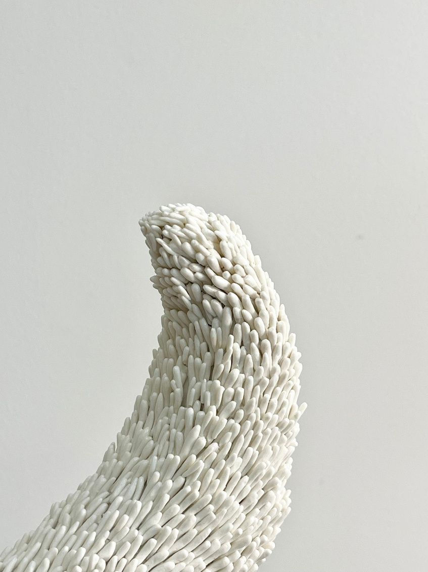Luna sculpture, crescent of white porcelain with pressed texture resting on a dark stoneware sphere — view 2