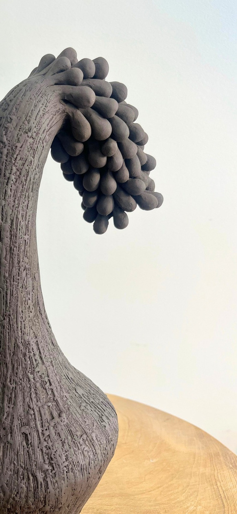 The gravity of sorrow sculpture, tall dark stoneware form with a curved neck bending under a dense cluster of rounded forms — view 3