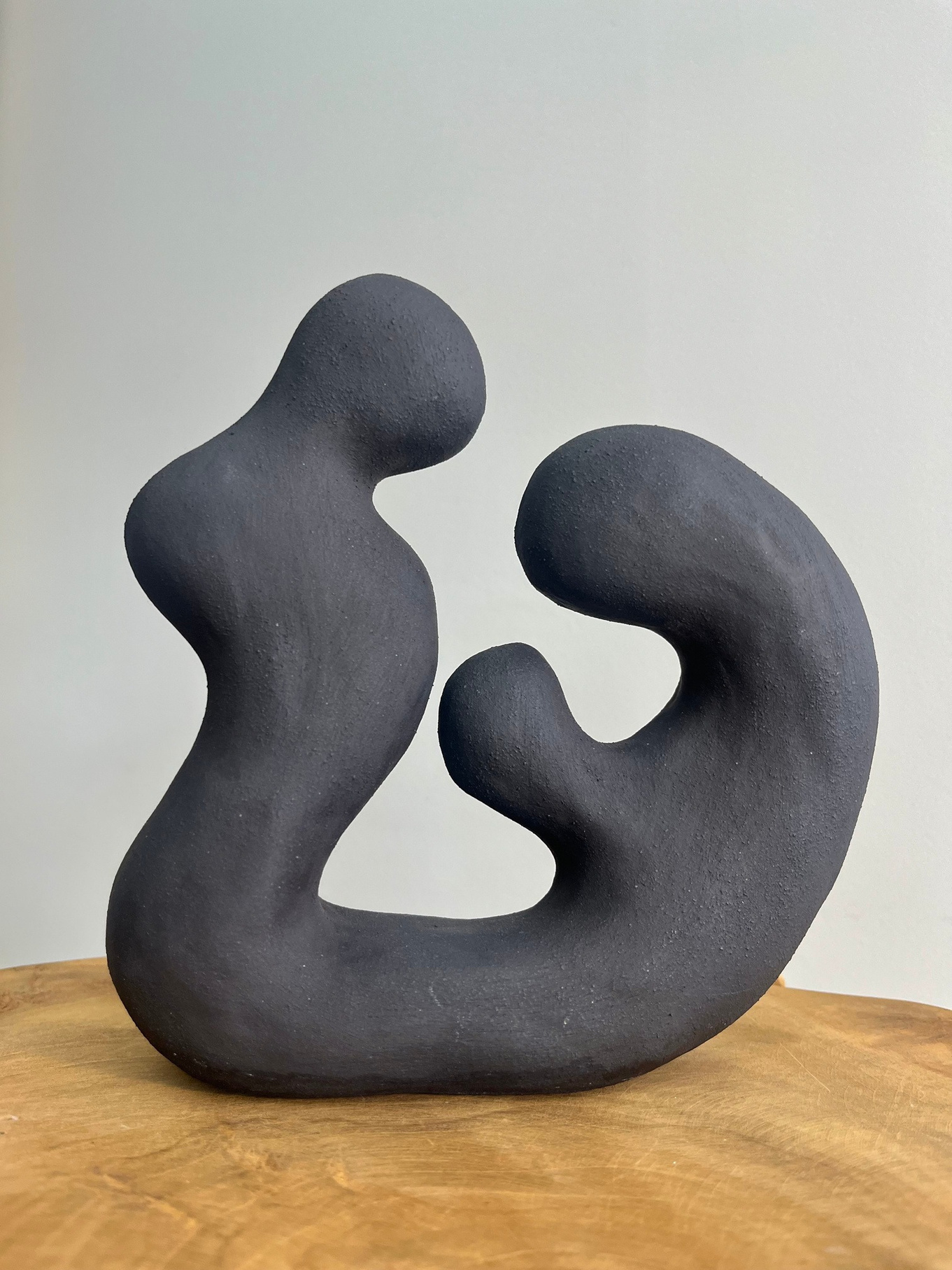 The shape of Us sculpture, two dark stoneware forms leaning into each other, smooth organic surfaces — view 2